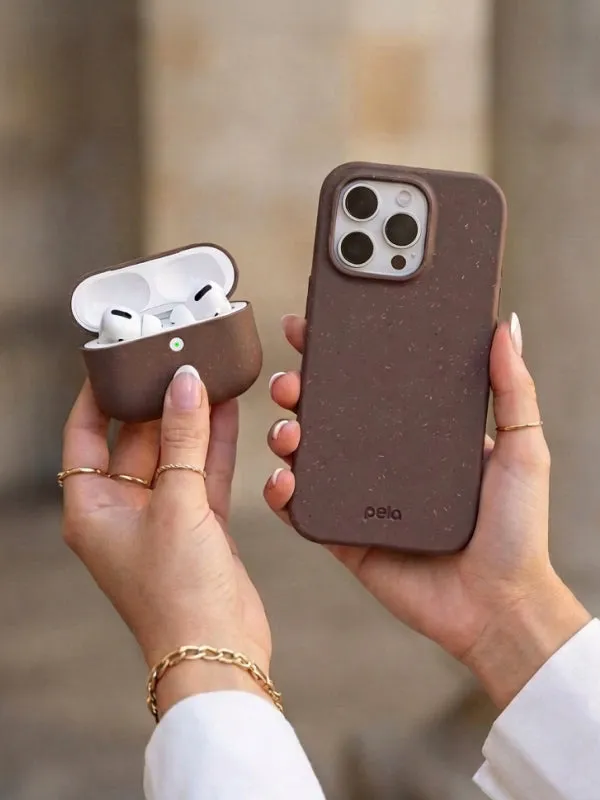Hands holding a brown Pela phone case next to a Pela AirPod case