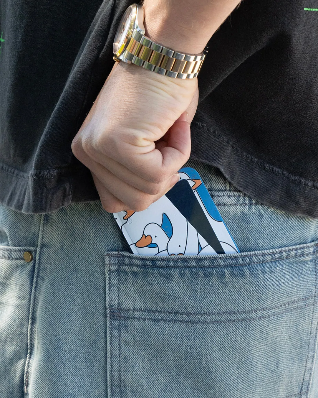 A hand sliding a Pela phone case into a jeans pocket