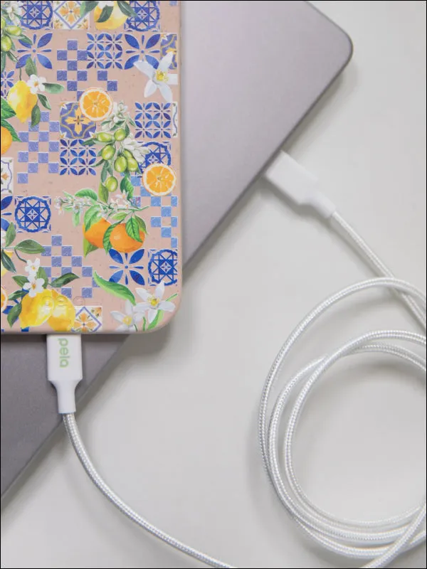 A Pela phone case with a tile pattern plugged into a white charging cable