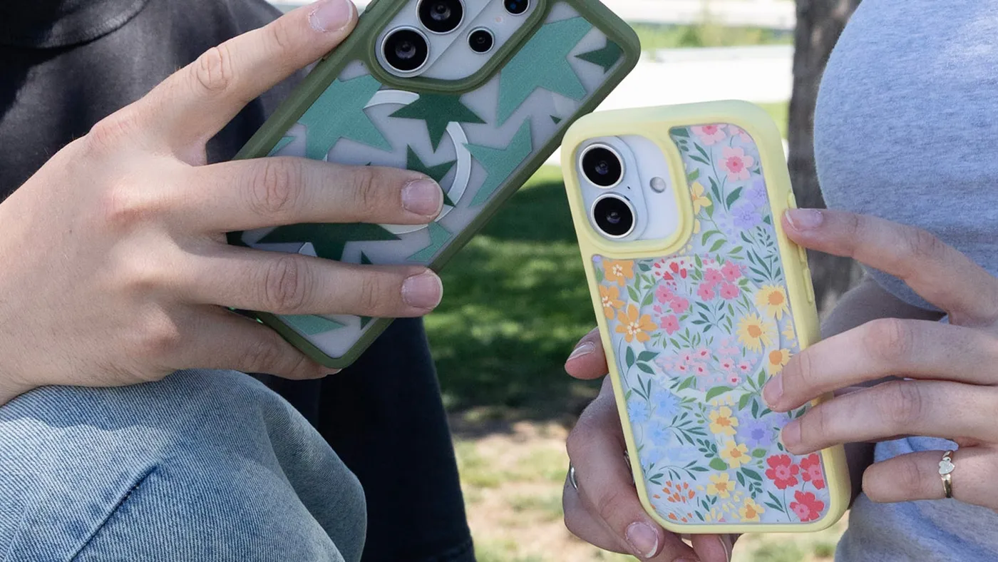 Two people holding Pela phone cases outdoors, one green and one with a yellow floral design