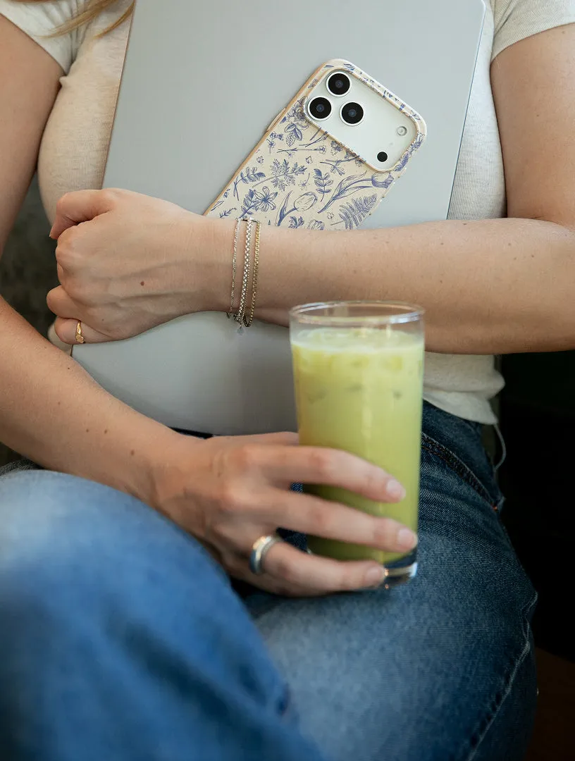A woman holding a phone with a Pela case while seated